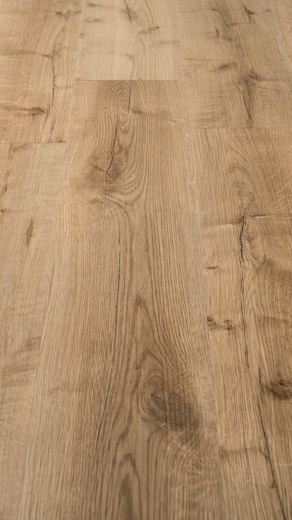 A close-up image of a vinyl flooring plank with a light oak tone and grain embossing.