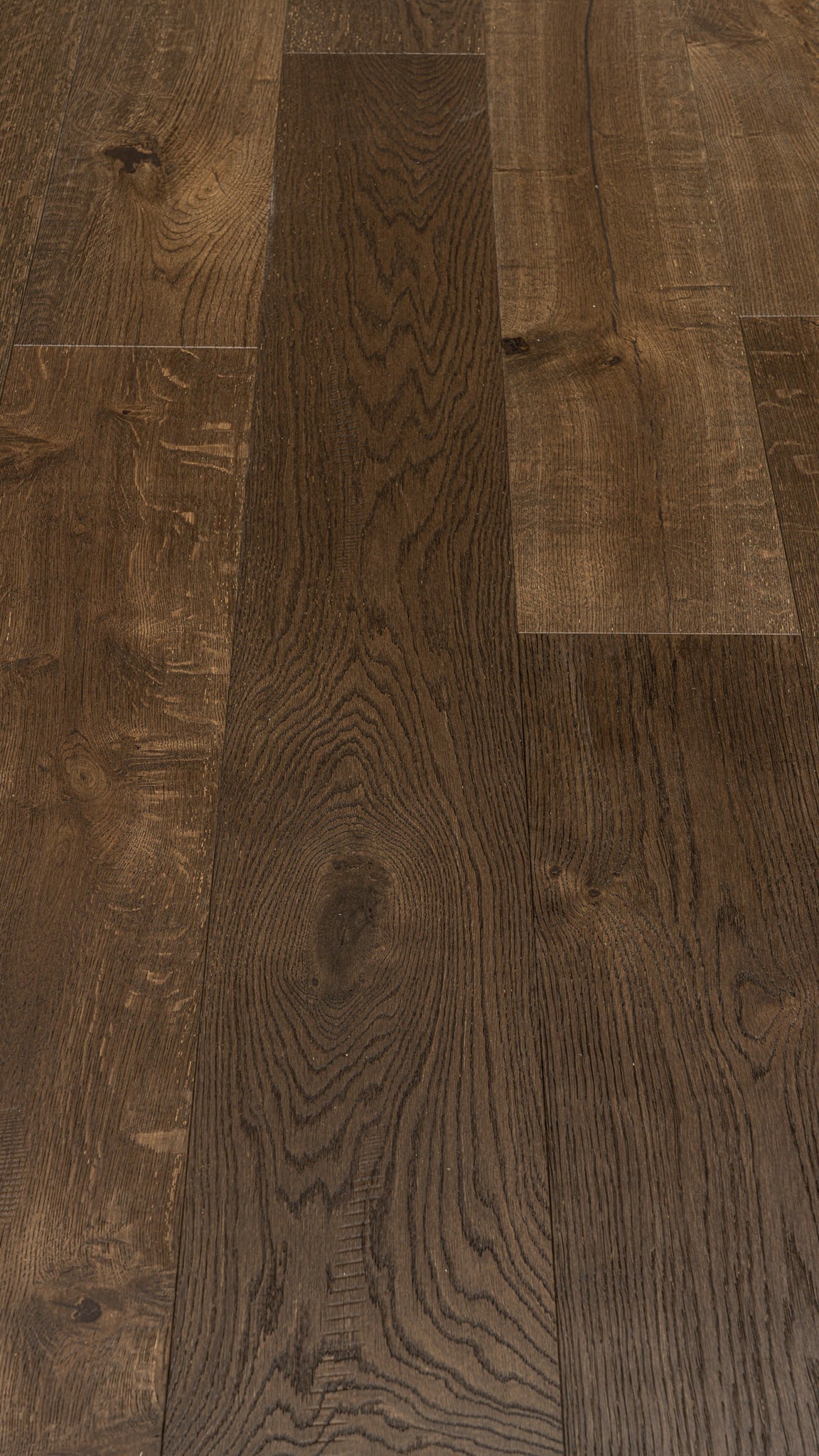 A picture showing Denver hardwood from the Wildwood Nature collection. The photo shows some minor variation from board to board. The hardwood is a dark brown smoked oak with a wire-brushed surface.