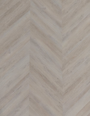 A picture showing the 6.5mm lvp flooring called Mumbai in the chevron pattern. This vinyl floor is uniquely crafted and can only be installed in the chevron pattern. It has a light grey-beige hue and silver chain embossing, giving the floor an ultra-realistic look.