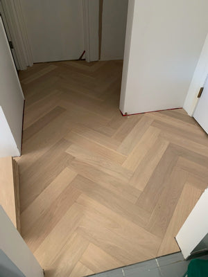 A picture showing Arvand herringbone installed in the hallway of a home. The hardwood is very clean looking and shows no knots, a quality of the high grade of hardwood used.