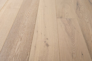 A picture of the oak  hardwood flooring called Dublin from the Wildwood Antique Collection, showing some minor knots and variation with a light, white-washed hue and beige tones.