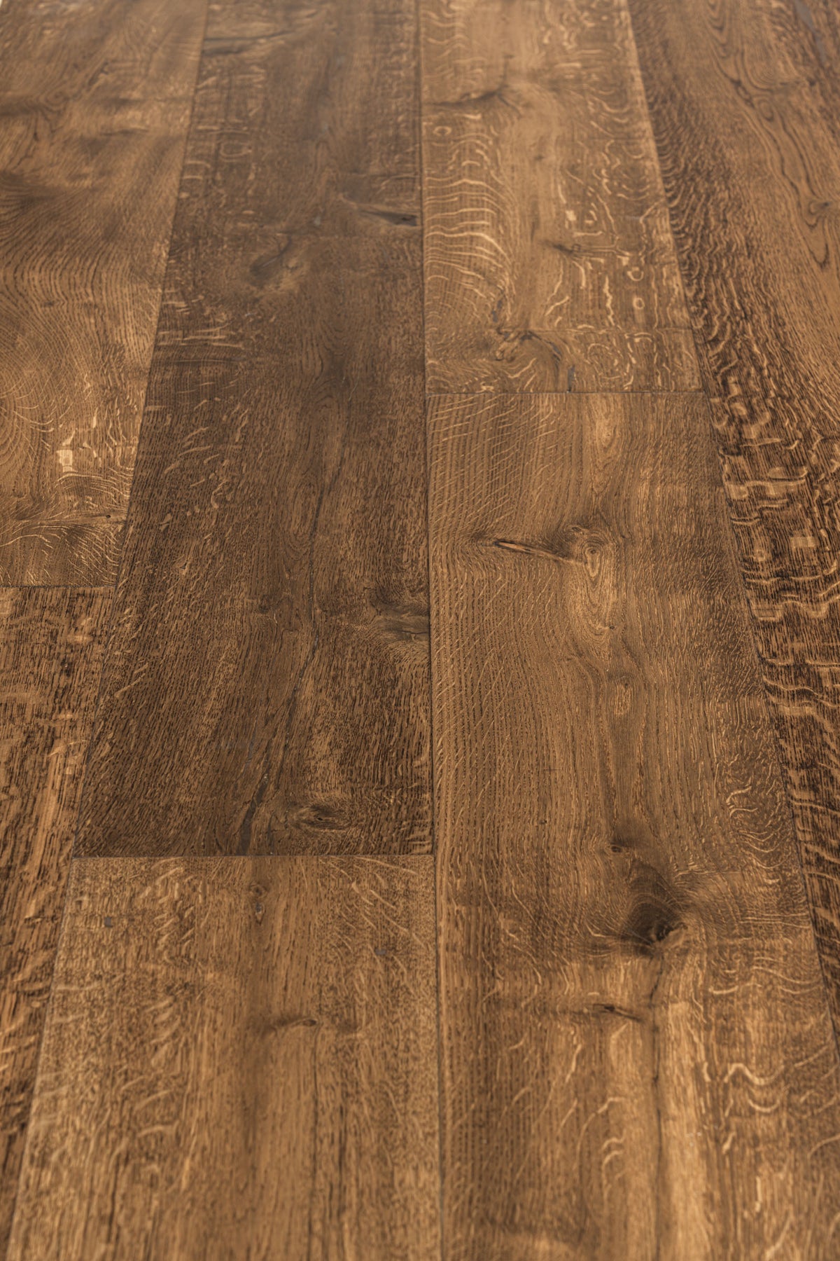 A picture showing the oak hardwood called Geneva from the Wildwood Nature Collection. The hardwood is a brown-amber colour, with some areas of darker tones and some with lighter tones. The floor is lightly hand scrapped and has a beautiful, rustic look, reminiscent of flooring found in old european castles.