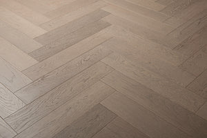 A photo of the hardwood called Milan in the herringone pattern. This oak hardwood features a muted grey stain and the high grade of the wood means there is minimal variation from board to board and little to no knots present.