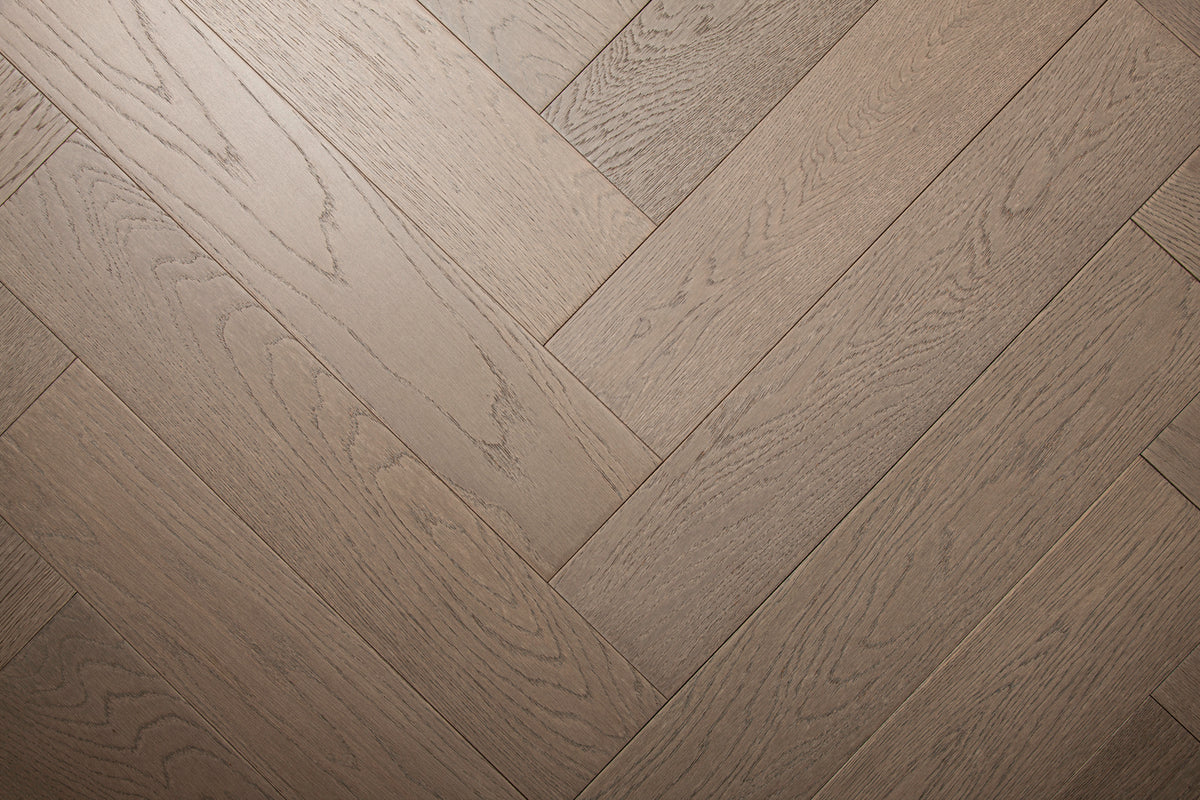A photo of the hardwood called Milan in the herringone pattern. This oak hardwood features a muted grey stain and the high grade of the wood means there is minimal variation from board to board and little to no knots present.