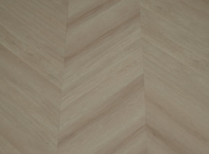 A picture showing the 6.5mm lvp flooring called Pompeii in the chevron pattern. This vinyl floor is uniquely crafted and can only be installed in the chevron pattern. It has a light medium beige hue and silver chain embossing, giving the floor an ultra-realistic look.