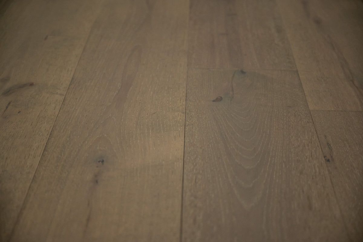 A picture of the oak  hardwood flooring called Oak Natural from the Wildwood Antique Collection, showing some knots and variation with a brown-gray tone.