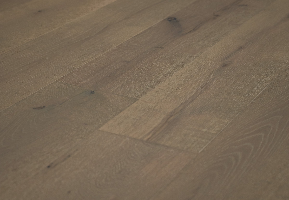 A picture of the oak  hardwood flooring called Oak Natural from the Wildwood Antique Collection, showing some knots and variation with a brown-gray tone.