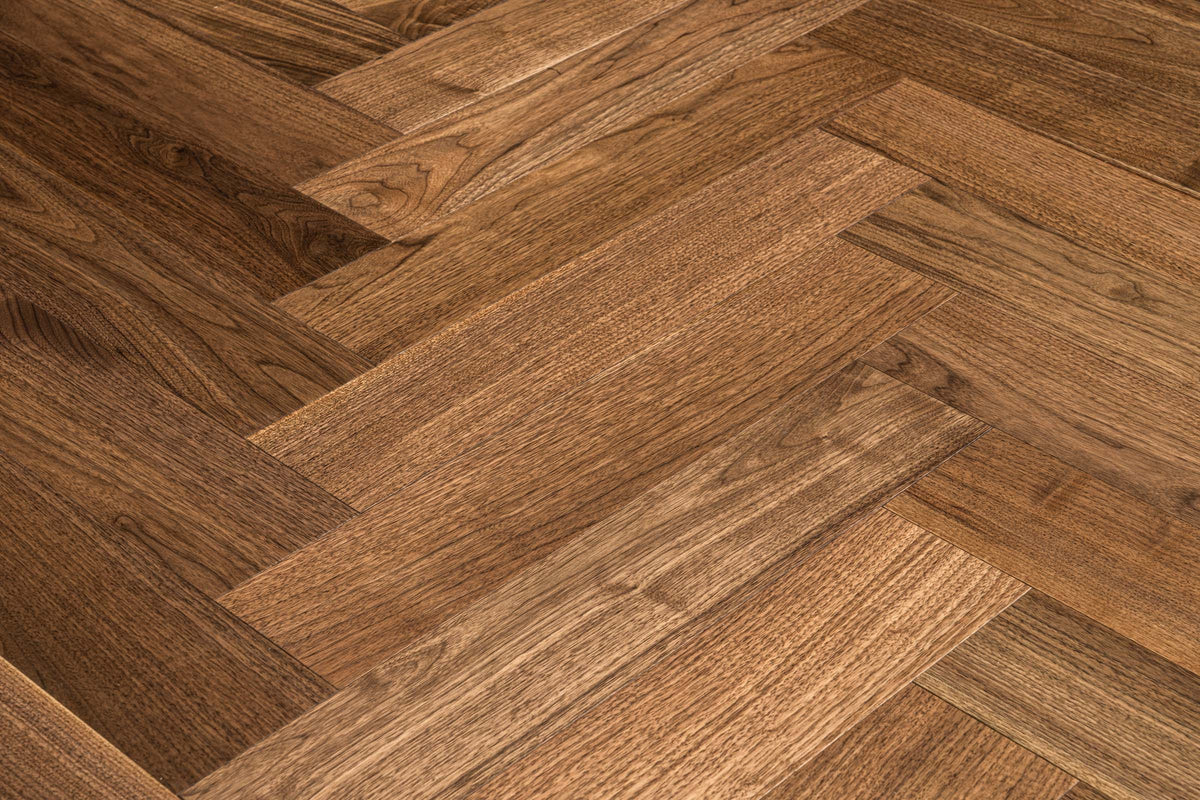 A picture of Walnut Natural Herringbone, from the Wildwood Nature Herringbone Collection. The hardwood is a warm brown walnut color, with some variation from board to board, characteristic of American Walnut.