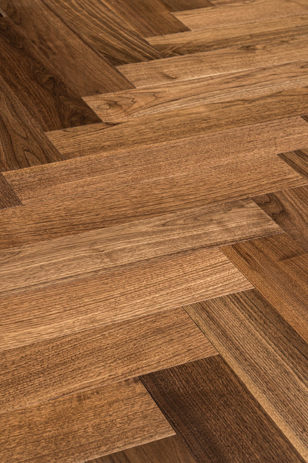 A picture of Walnut Natural Herringbone, from the Wildwood Nature Herringbone Collection. The hardwood is a warm brown walnut color, with some variation from board to board, characteristic of American Walnut.