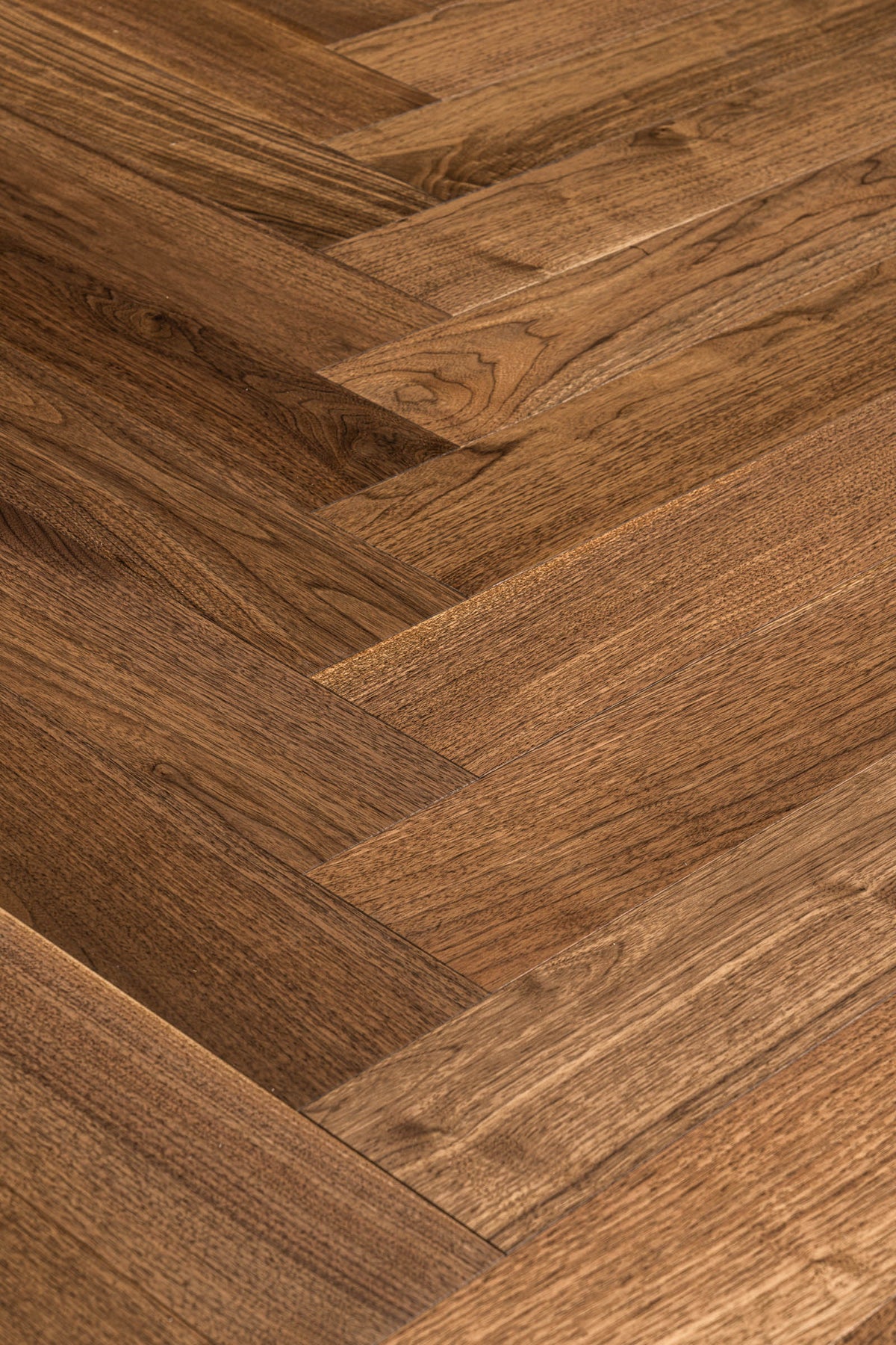 A picture of Walnut Natural Herringbone, from the Wildwood Nature Herringbone Collection. The hardwood is a warm brown walnut color, with some variation from board to board, characteristic of American Walnut.