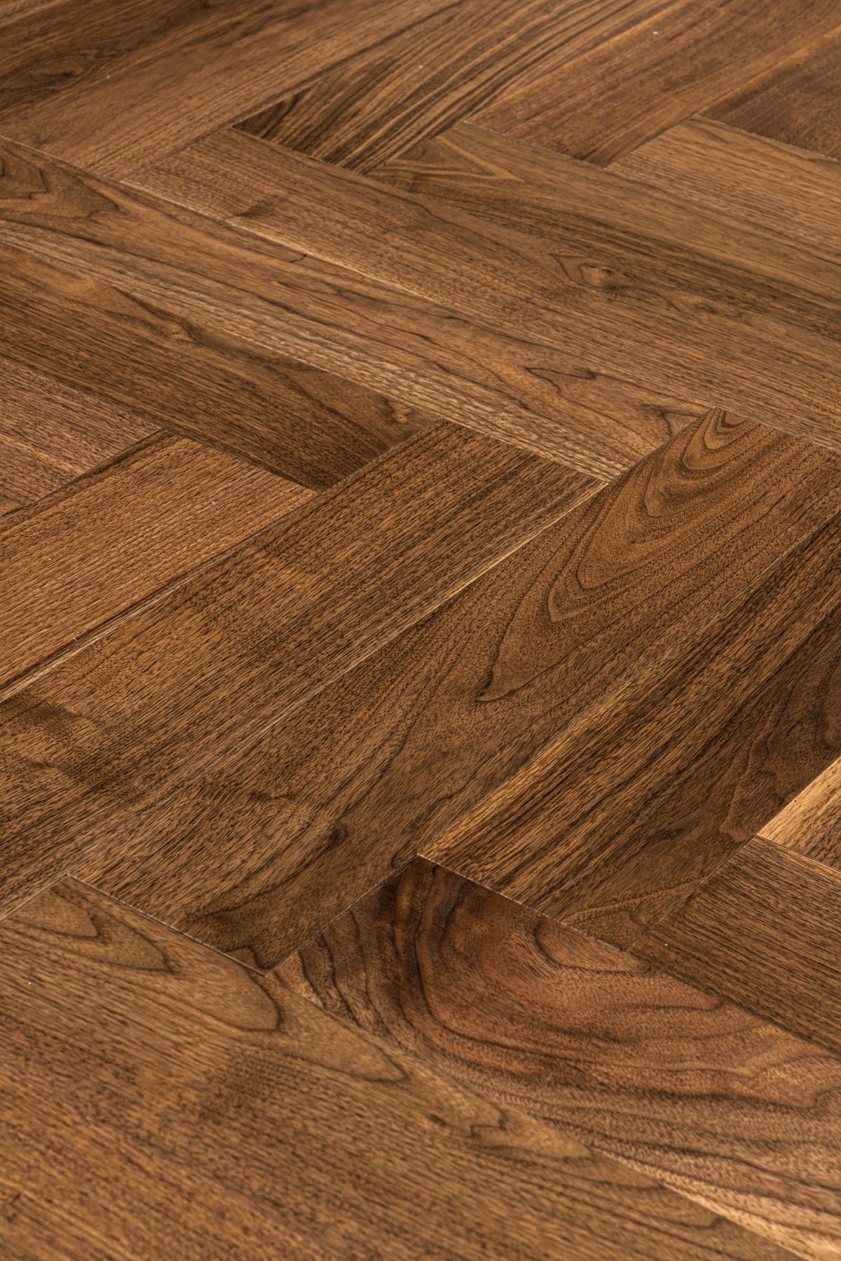 A picture of Walnut Natural Herringbone, from the Wildwood Nature Herringbone Collection. The hardwood is a warm brown walnut color, with some variation from board to board, characteristic of American Walnut.