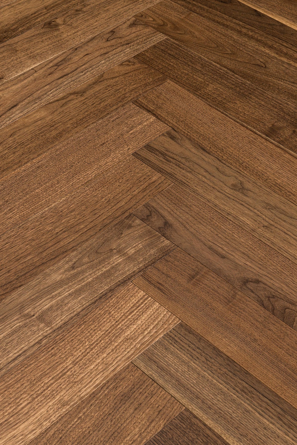 A picture of Walnut Natural Herringbone, from the Wildwood Nature Herringbone Collection. The hardwood is a warm brown walnut color, with some variation from board to board, characteristic of American Walnut.