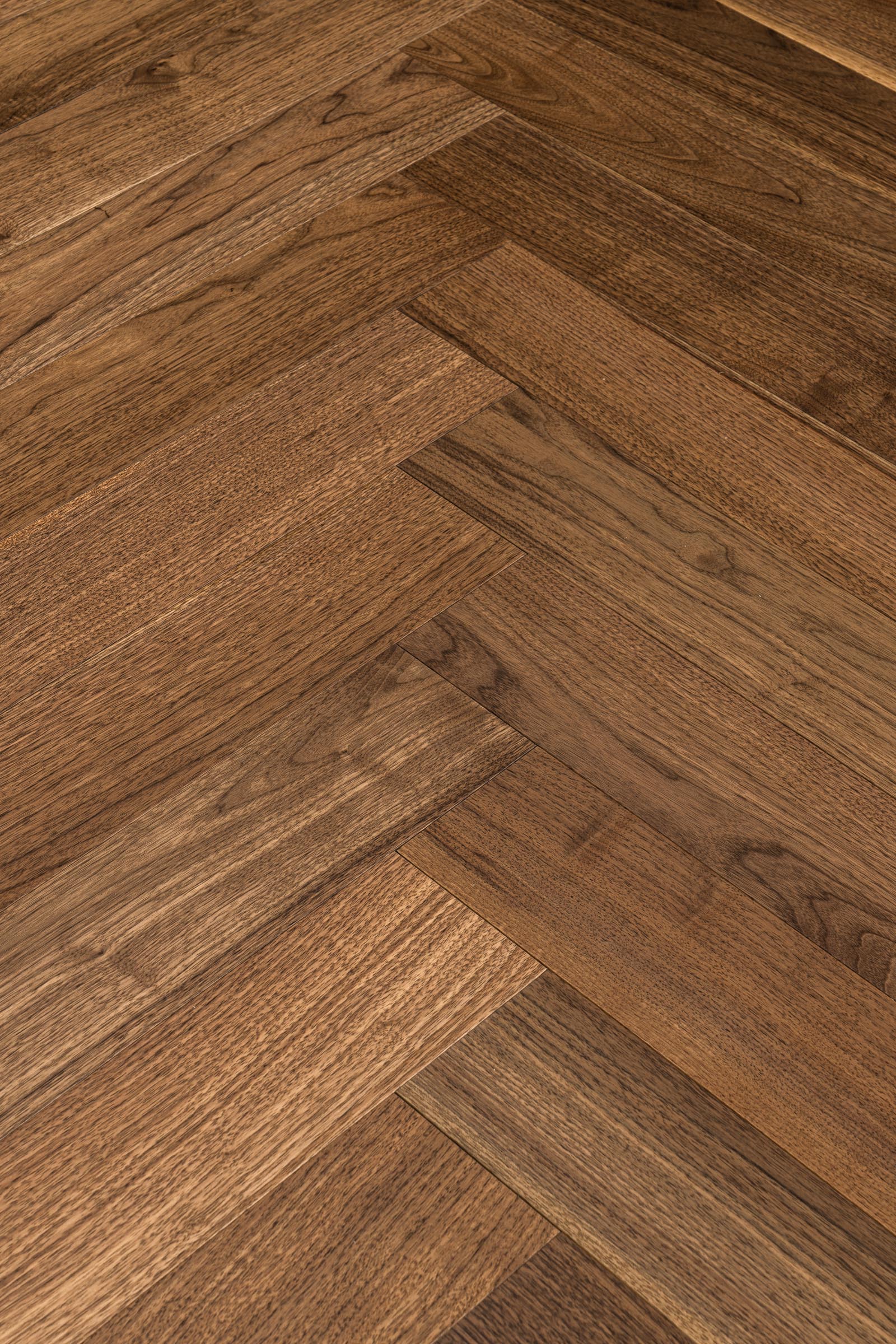 A picture of Walnut Natural Herringbone, from the Wildwood Nature Herringbone Collection. The hardwood is a warm brown walnut color, with some variation from board to board, characteristic of American Walnut.
