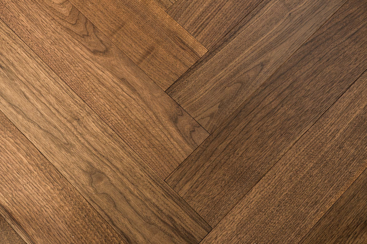 A picture of Walnut Natural Herringbone, from the Wildwood Nature Herringbone Collection. The hardwood is a warm brown walnut color, with some variation from board to board, characteristic of American Walnut.